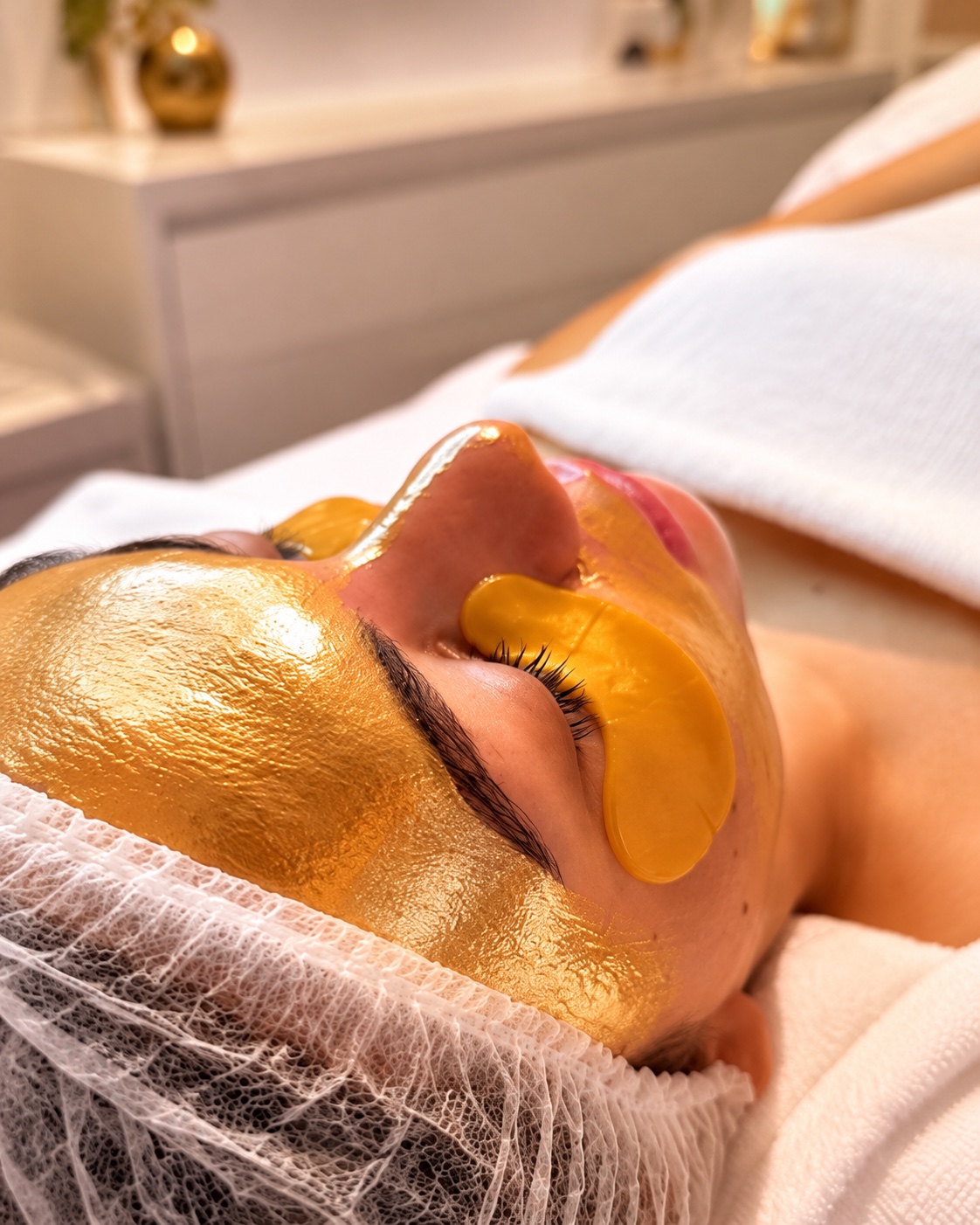 Cliente relaxando com máscara facial dourada durante um atendimento na Drena